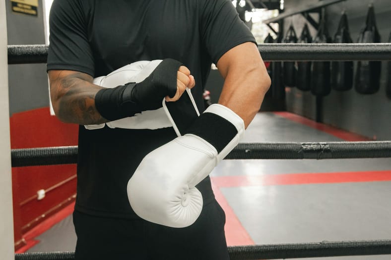 man putting on white boxing gloves